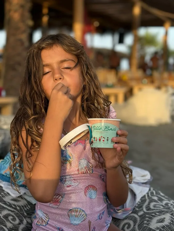 Djevojčica na plaži jede sladoled iz čašice