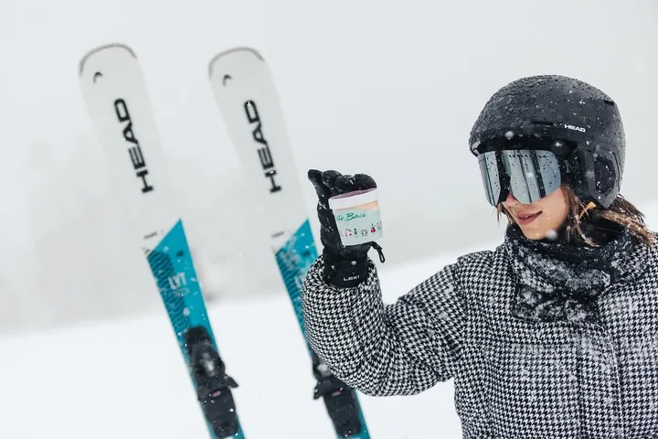 Skijašica pored skija drži čašicu sladoleda